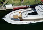 Aerial view of a white luxury motor yacht docked at a marina with teak deck and seating area on the stern edge.
