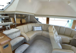 Luxurious beige leather seating area on a yacht, with a curved sofa and wooden trim nearby.