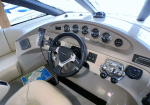 Boat cockpit interior with steering wheel, gauges, throttles, and a map on the seat.
