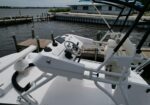 White powerboat cockpit with steering wheel, gauges, and a tablet-style display, dock and water in the background.