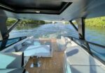Luxurious yacht deck with pale blue seating and a central table, waterway ahead.
