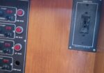 Wooden wall with vertical marina control panels showing bilge pump switches, red push buttons, and knobs; right panel labeled WINDLASS with a toggle switch.