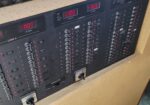 Electrical control panel with many toggle switches and red indicator lights labeled LOAD A and LOAD B.