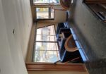 Interior of a boat’s living area with a dark stone countertop and wooden cabinetry, windows showing a marina outside