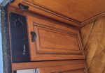 Black GE Monogram dishwasher installed under granite countertop, flanked by ornate wooden kitchen cabinets with carved trim.