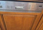 Built-in Miele dishwasher with a stainless steel control panel set into oak kitchen cabinets.