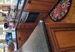 Boat-style kitchen with dark granite countertops, warm wooden cabinets, and a built-in oven under a countertop island.