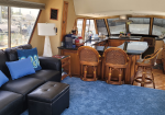 Luxurious yacht interior with a leather sofa, blue cushions, and a polished bar area with wooden cabinets.