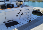 White motor yacht with a dog logo and 'RASCAL' on the stern, docked at Alameda, CA marina.